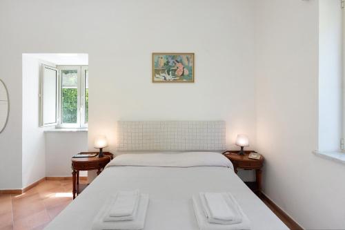 a white bedroom with a bed and two windows at Appartamento Anna in Meta