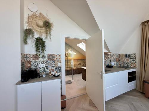 an attic kitchen with white cabinets and a staircase at Mel's Pintxos winebar & Aparthotel in Zandvoort