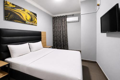 a bedroom with a white bed and a flat screen tv at Hotel Metro Lodge Beach in Durban