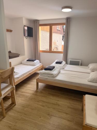 two beds in a room with a window at Résidence le Prorel - Serre chevalier in Saint-Chaffrey