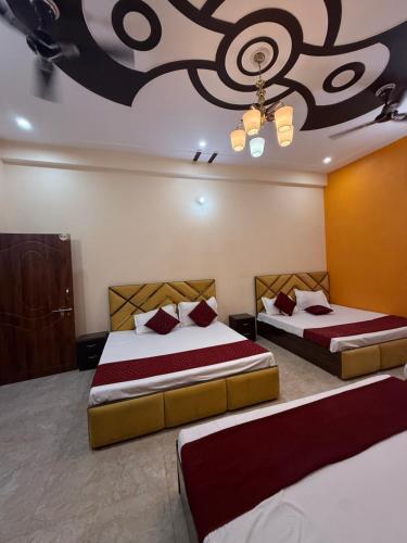 a bedroom with two beds and a ceiling with a painting at Hotel New Vedas Villa 15 mints From Ram Temple in Ayodhya