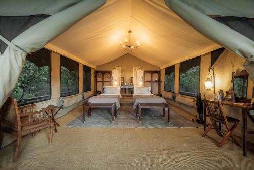 a tent with a bed and chairs in a room at Elephant Pepper Camp in Masai Mara