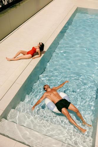 a man and woman swimming in a swimming pool at Hard Rock Hotel Madrid in Madrid