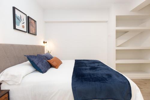 a bedroom with a bed with white sheets and blue pillows at Xena Cucuraza by BeValle in Panticosa