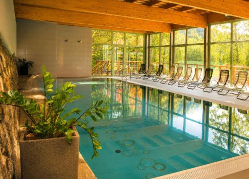 una piscina con sedie in una stanza con finestre di Hotel Rusava a Rusava