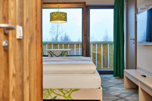 two beds in a room with a balcony at Explorer Hotel Bayrischzell in Bayrischzell
