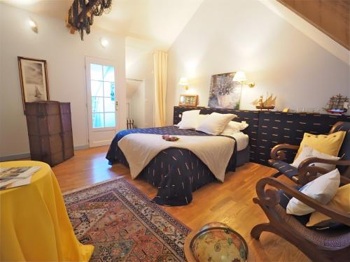 a bedroom with a bed and chairs in a room at La Bruyère-Maison d'hôtes-Piscine in May-sur-Orne