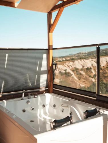 a bath tub in a bathroom with two large windows at Cappadocia Pegasos Cave Suite Hotel in Uçhisar