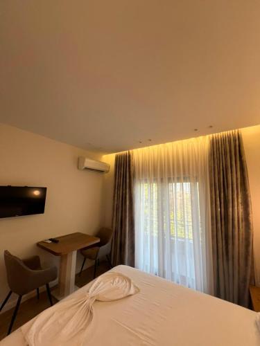 a hotel room with a bed and a desk and a window at Hotel Restorant Riza in Tirana