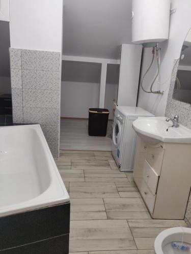 a bathroom with a tub and a sink and a washing machine at Enjoy strudio apartment M in Murfatlar