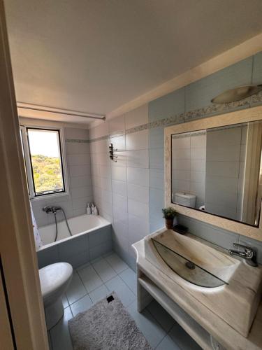 a bathroom with a tub and a sink and a mirror at Flowerhouse in Porto Heli