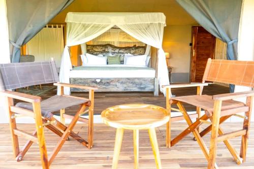 a room with two chairs and a bed and a table at Royal Horizon Adventure in Sekenani