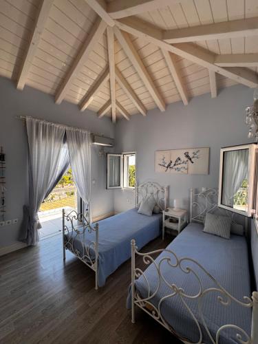 two beds in a bedroom with wooden ceilings at Flowerhouse in Porto Heli