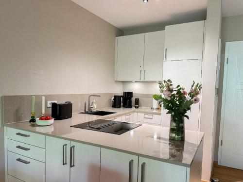 a kitchen with white cabinets and a vase of flowers at Ferienwohnung Lütte Bleev am Dümmer See in Lembruch
