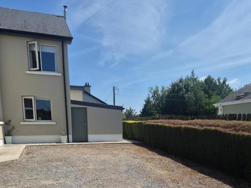 ein weißes Haus mit einer Auffahrt neben einer Hecke in der Unterkunft corrygarry in Kingscourt