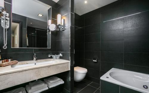 a bathroom with a sink and a toilet and a tub at Admiral Grand Hotel in Slano