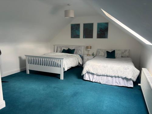 two beds in a room with blue carpet at Cosy East Clare Apartment in Coolcoosaun