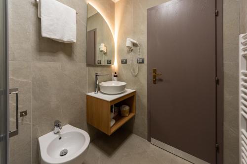 a bathroom with a sink and a toilet and a mirror at Kyrr Smart Mountain Retreat in Moena