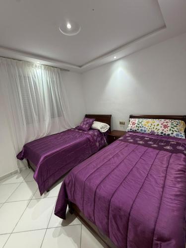 two beds in a bedroom with purple comforter at Apartment with pool in Asilah