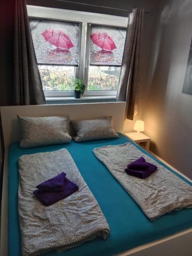 a bed with two pillows and a window with umbrellas at FjordHome in Flensburg