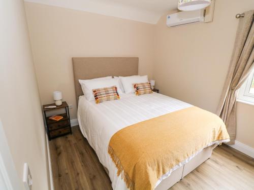 a bedroom with a large white bed with two pillows at Mayfly Cottage in Clonbur