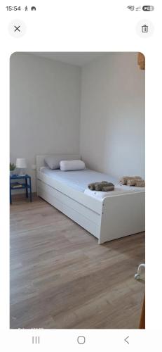 a white bed in a room with a wooden floor at Under the Mediterranean sky in Terrassa