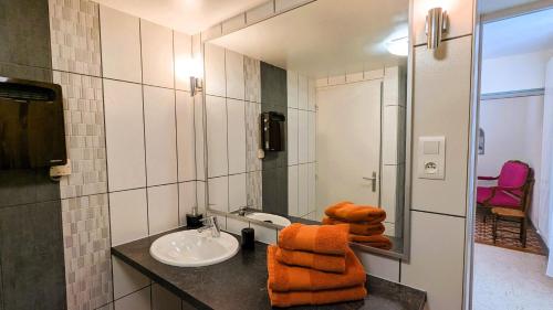 a bathroom with a sink and orange towels on a counter at Les Chambres de Grangette in Thury