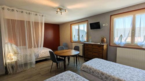 a bedroom with two beds and a table and a desk at Les Chambres de Grangette in Thury