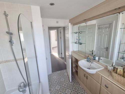 a bathroom with a sink and a shower at Beach Break Aberavon Holiday Home by the Sea in Port Talbot