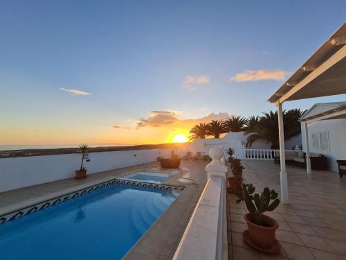 a swimming pool on the side of a house with the sunset at La Ventana al Mar in Güime