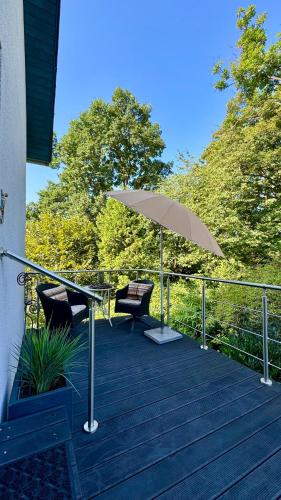 a wooden deck with an umbrella and two chairs at Ferienapartment Elegance in Michelstadt