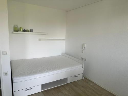 a small white room with a bed and a shelf at Helles Apartment mit Self Check-in in Nuremberg