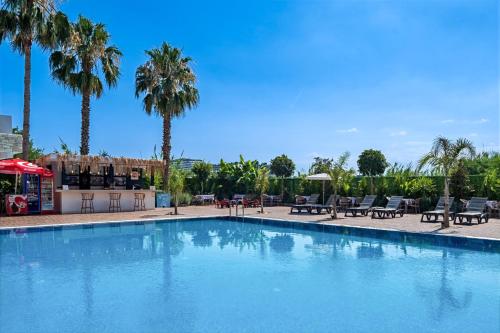 a large swimming pool with palm trees in the background at Laristone Suite Spa Hotel in Antalya