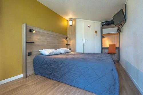 a bedroom with a blue bed with a tv on the wall at Premiere Classe Rodez in Rodez