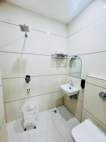 a white bathroom with a toilet and a sink at Hotel Grand Royal Sandhu in Amritsar
