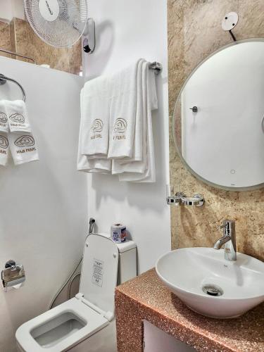 a bathroom with a sink and a toilet and a mirror at Maji Pearl Hotel & Spa in Nungwi