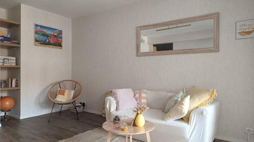 a living room with a white couch and a mirror at Appartement L'esprit marin in Villers-sur-Mer