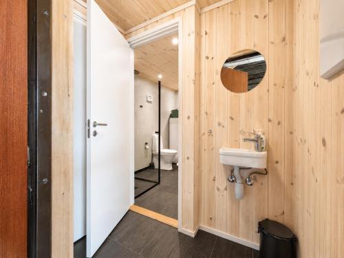 a bathroom with wooden walls and a sink and a mirror at Architect designed sleeping box in barn in Nos