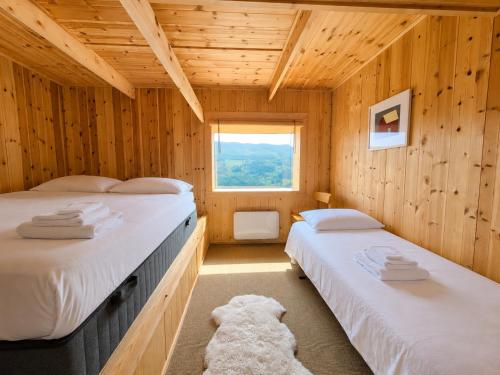 two beds in a wooden room with a window at Architect designed sleeping box in barn in Nos