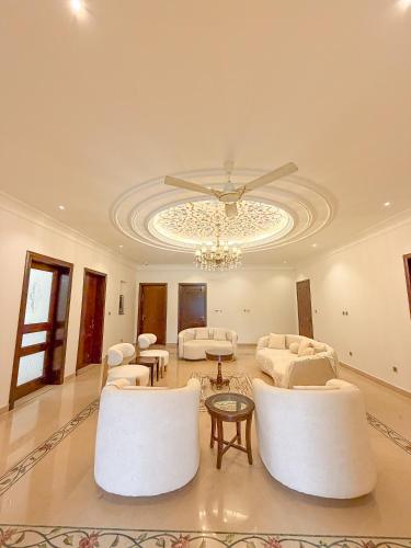 a living room with white furniture and a chandelier at Hamzas production in Islamabad