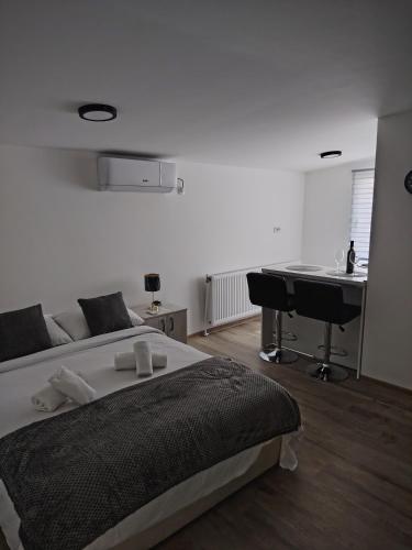 a white bedroom with a bed and a desk at Apartmani Hilston in Vršac