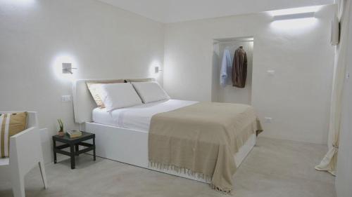 a white bedroom with a bed and a side table at Casa Fidelia in Ceglie Messapica