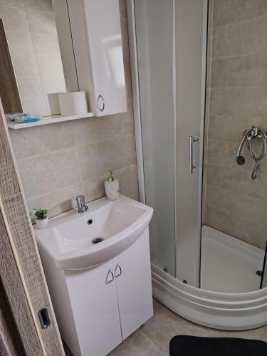 a bathroom with a white sink and a shower at Apartmani Hilston in Vršac