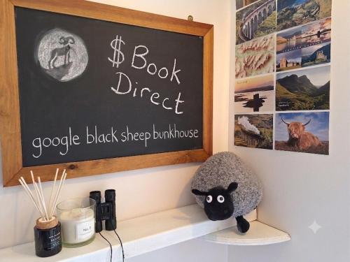 a shelf with a book direct sign and a stuffed animal at Black Sheep Bunkhouse in Fort William