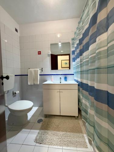a bathroom with a toilet and a sink and a mirror at Caravela B in Armação de Pêra