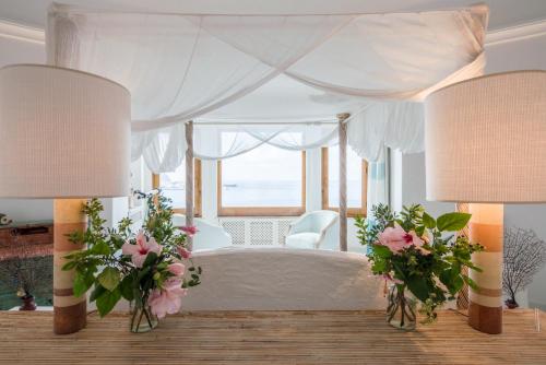 イスキアにあるTorre dell'Aquilaのベッドルーム(ピンクの花が咲く白い天蓋付きベッド付)