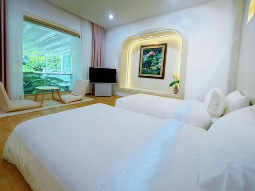 a bedroom with two white beds and a window at Kharin guesthouse in Nakhon Phanom