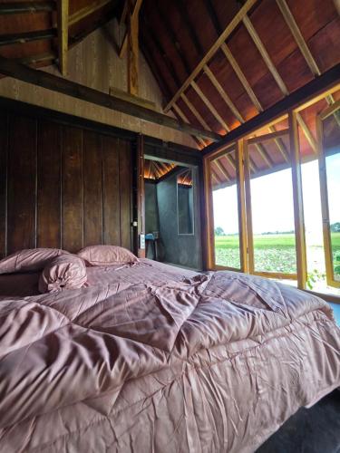 a large bed in a wooden room with windows at Aura V Bungalow in Praya