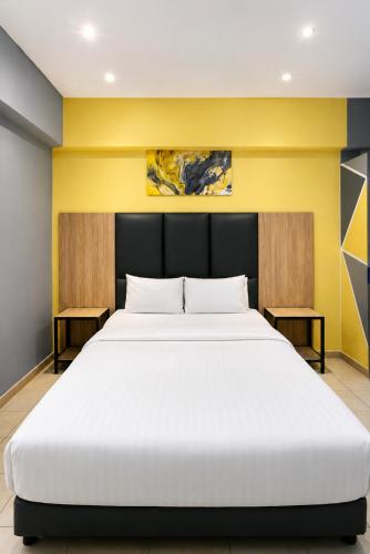 a large white bed in a room with a yellow wall at Hotel Metro Lodge Xpress in Durban