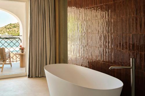 a bath tub in a bathroom with a balcony at W Sardinia - Poltu Quatu in Porto Cervo
